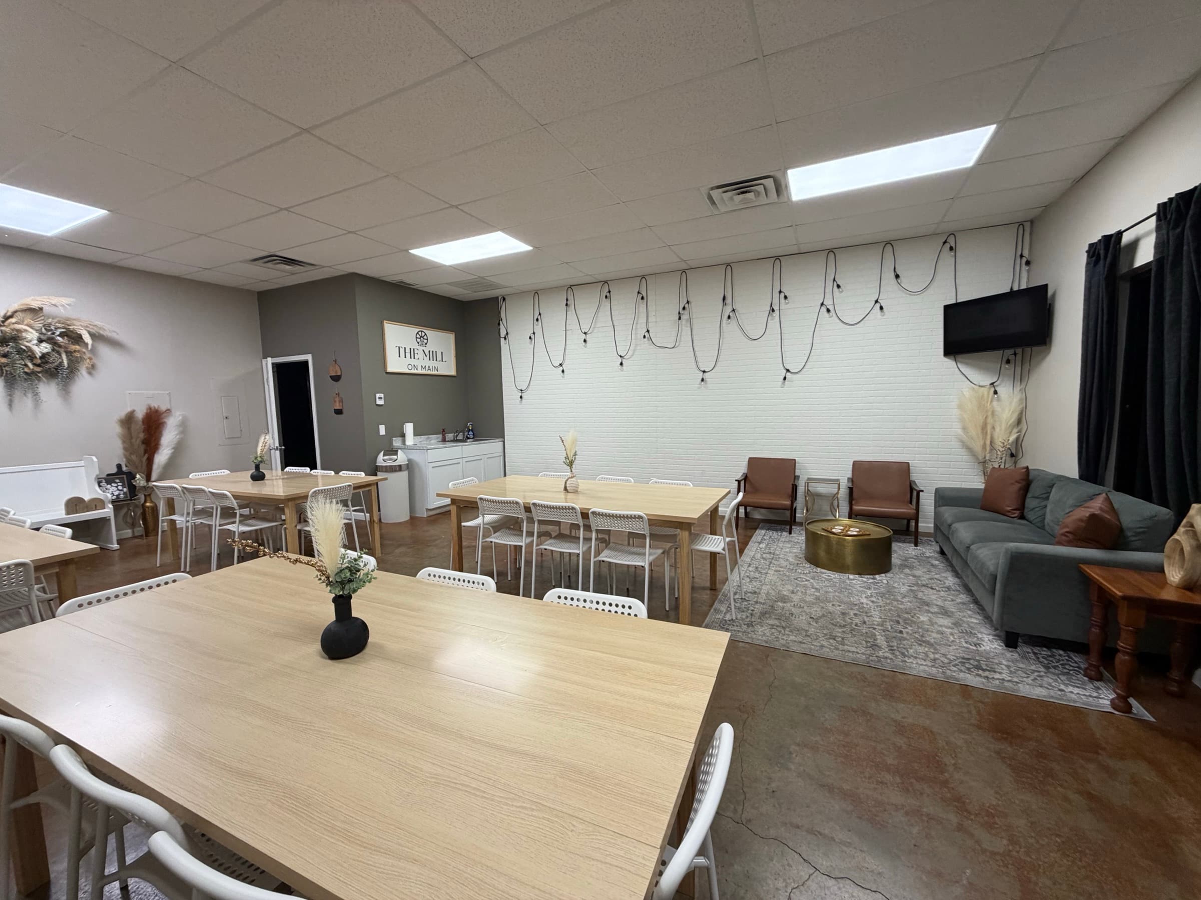 The Mill On Main room set with tables, chairs, lounge seating, and a television