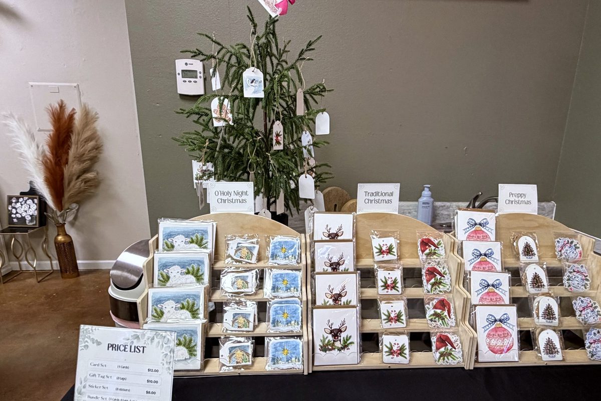 Vendor table of handmade greeting cards in wooden displays beside a small decorated tree
